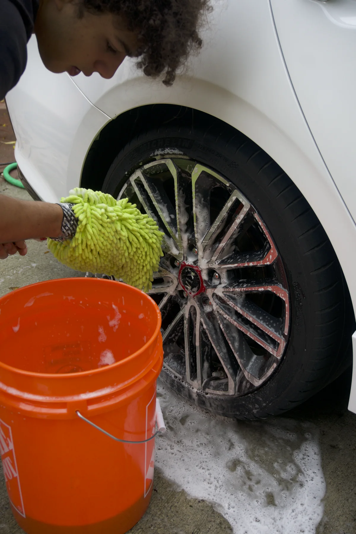 A detailer washing a car wheel