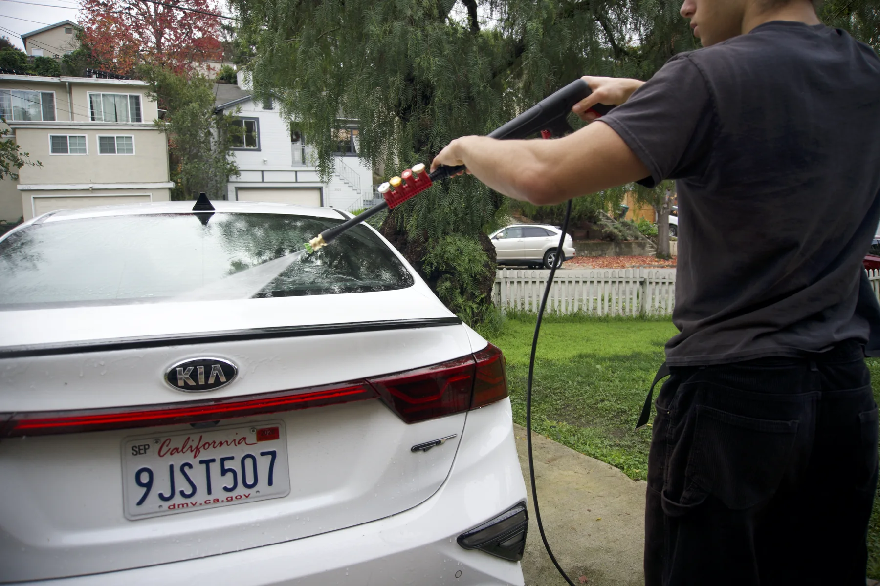 A detailer pressure washing a white car
